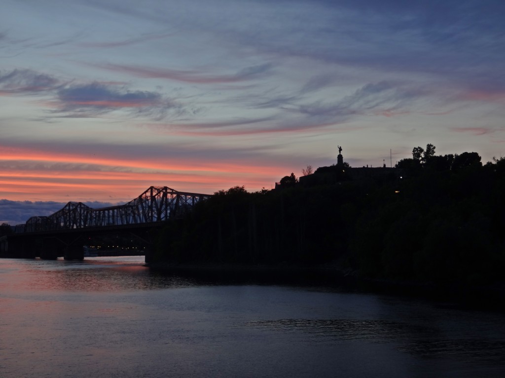 The Alexandra Bridge and Statue of Samuel de Champlain stand silhouetted against wispy blue clouds and glowing pink bands of the dusk sky.