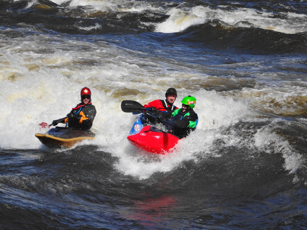 Three kayakers jostle in friendly competition for their place on "The Wave".