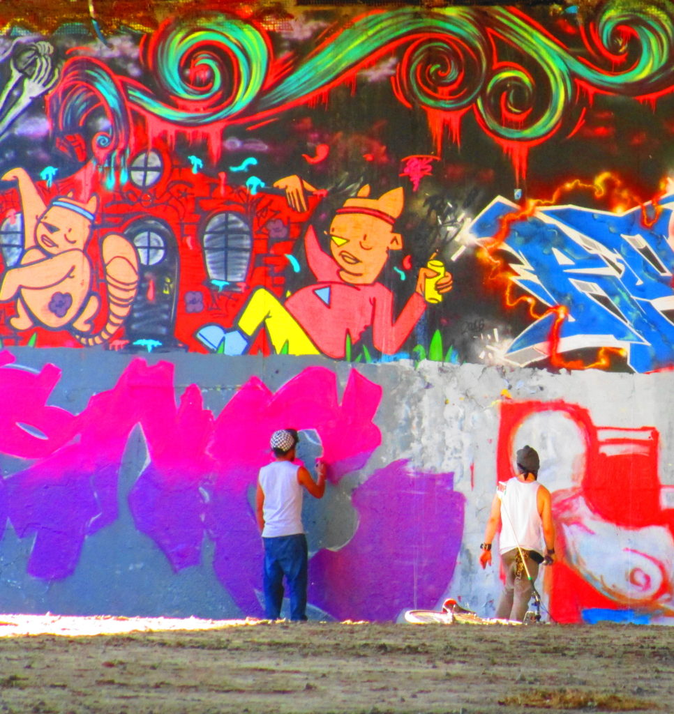 Two artists work on the graffiti wall at the House of PainT under the Dunbar Bridge.