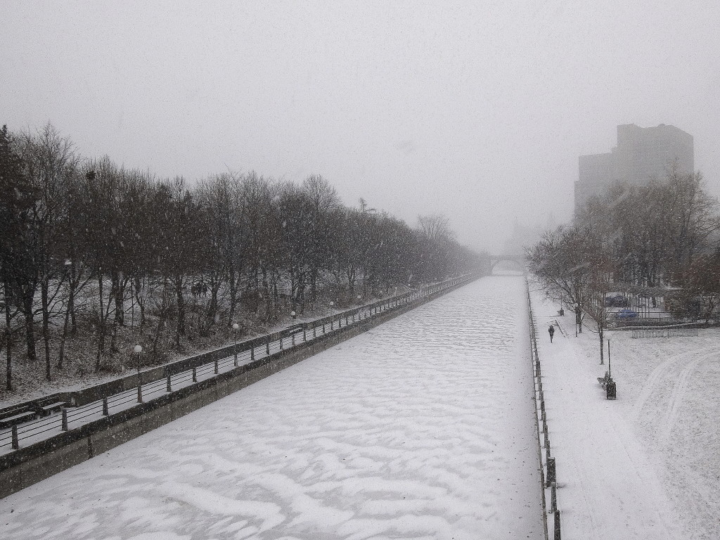 A winter scene from the Corkstown Bridge, with snow blowing and drifting on the frozen Rideau Canal