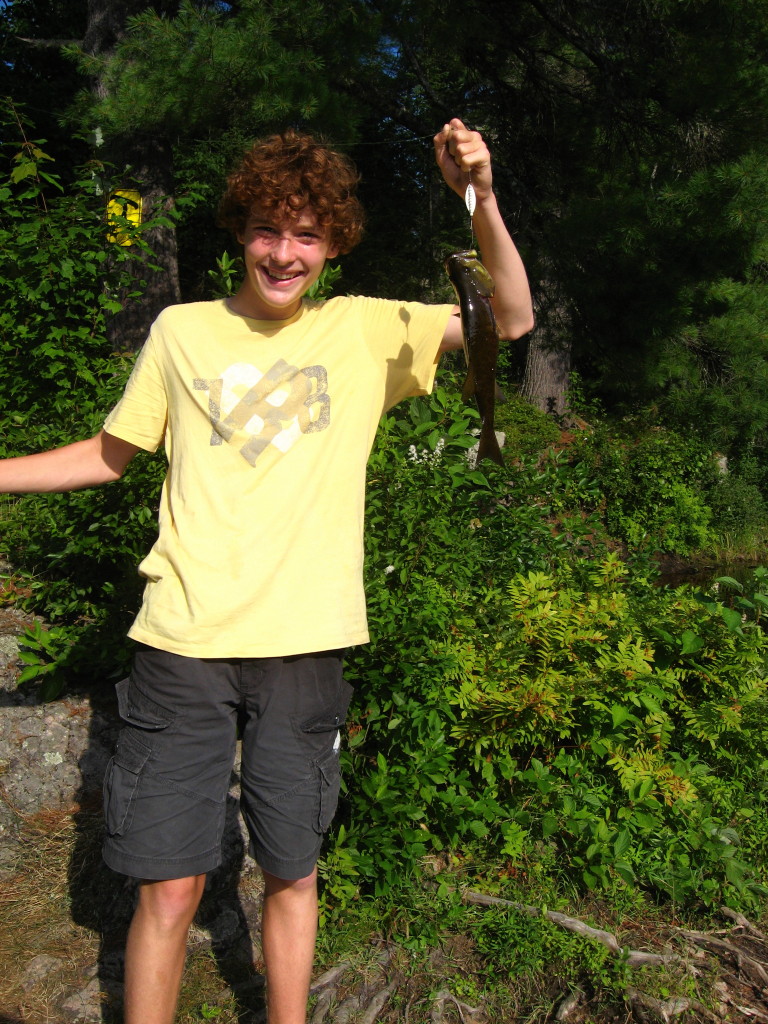 A teenage boy holds a largemouth bass.