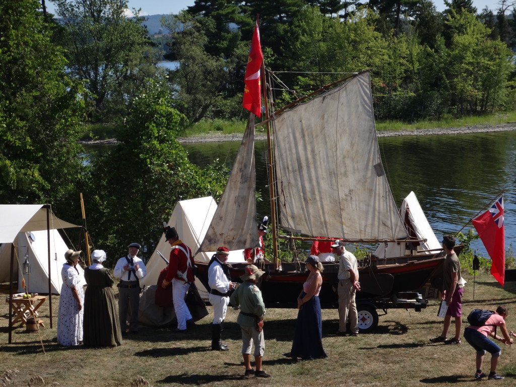 Exhibitors in period costume stand before a reconstruction of a traditional river sailboat at Riverfest at Pinhey's Point Historical Site.