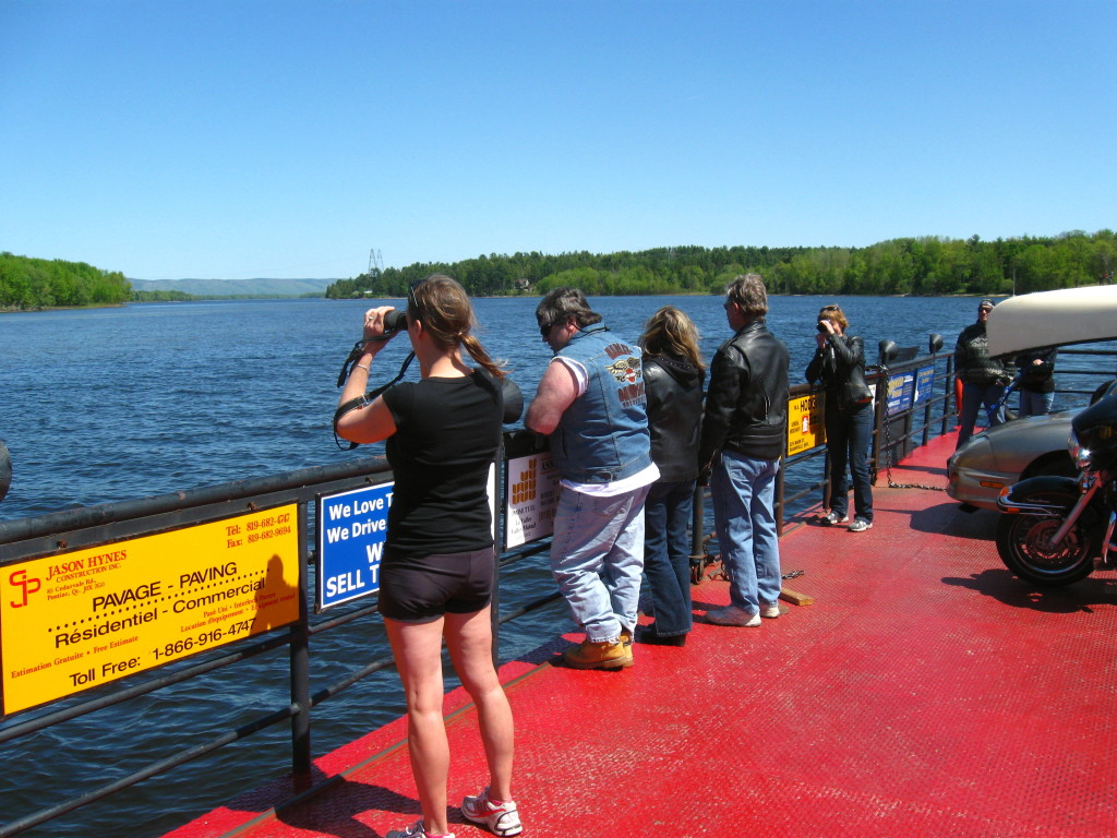 A group of people look out over the Ottawa River from the deck of the Quyon Car Ferry.