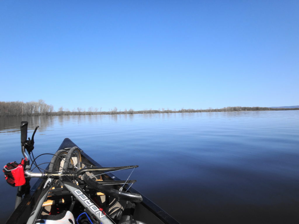 The bow of a canoe cuts through glassy water at Shirley's Bay. A bicycle lies in the canoe.