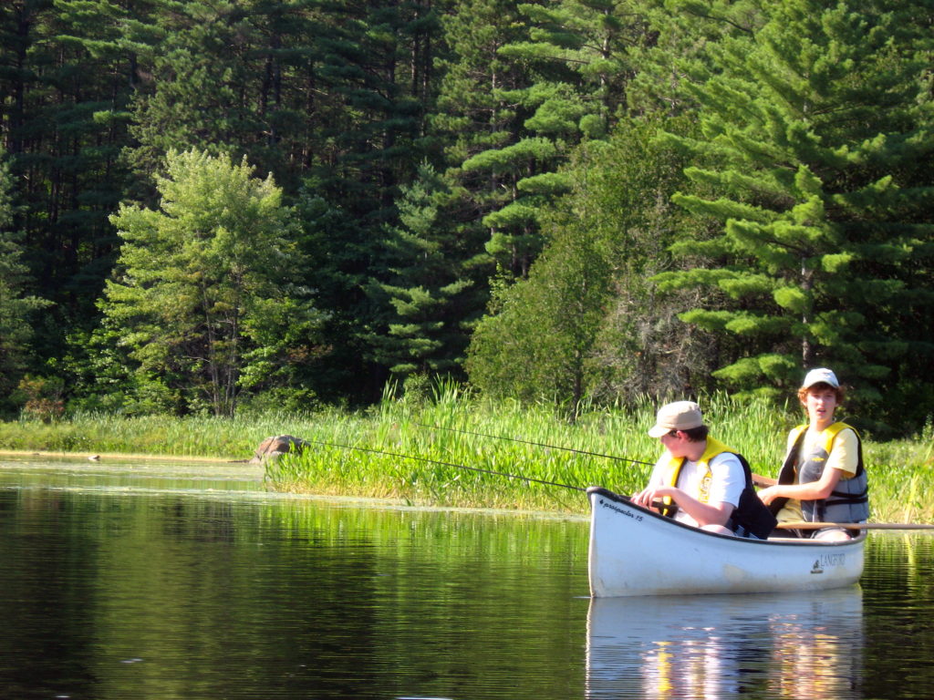 Two teenagers fish from a canoe in Algonquin Park.